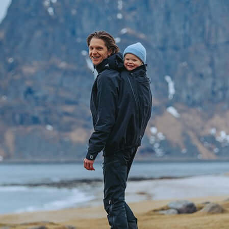 Mamalila Explorer Dad Waterproof Babywearing Shell Jacket - Black being worn outdoors by a dad with his baby | Babymaxi