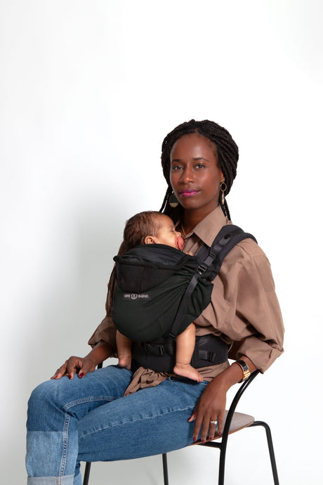 Woman using Love Radius HoodieCarrier 2 in Black Forest to carry her baby comfortably.