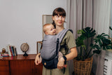 LennyLamb LennyLight - Little Herringbone Ombre Grey baby carrier with a smiling baby in a cozy indoor setting | Babymaxi
