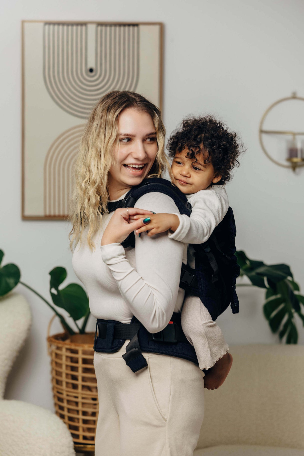 A happy mother carrying her toddler in the LennyLamb LennyPreschool (up to 30kg) - Little Herringbone Ebony Black | Babymaxi