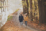 Two women walking along a serene autumn path near a canal, surrounded by colorful leaves | Babymaxi