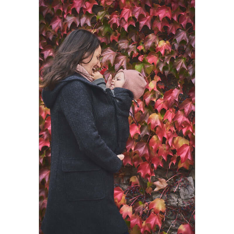 Mamalila Hooded Babywearing Coat Vienna - Anthracite worn by mother with baby, surrounded by colorful autumn leaves | Babymaxi