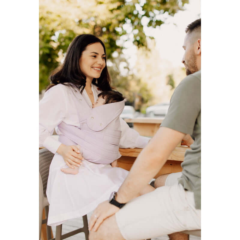 Mom wearing Marsupi Breeze - Lilac baby carrier comfortably at a cafe, showcasing ergonomic design for newborns | Babymaxi