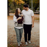 Couple walking outdoors with baby in Marsupi Classic - Berry baby carrier, showcasing comfort and ergonomic design | Babymaxi