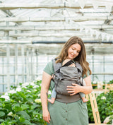 Neko Switch Baby Carrier - Bold, 2 extra hoods being used by a smiling parent in a greenhouse environment | Babymaxi