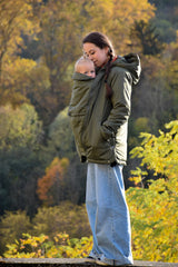 Mamalila Boston Babywearing Jacket Olive, mom wearing baby in carrier jacket on an autumn walk