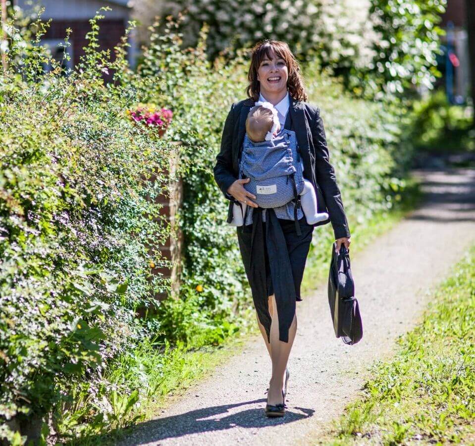 Happy parent wearing the Storchenwiege Talemo Half-Buckle Baby Carrier - Leo Black White while walking outdoors | Babymaxi