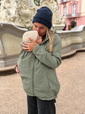 Mamalila Allrounder Winter softshell babywearing jacket in agave green, mum carrying her baby on the front under the jacket